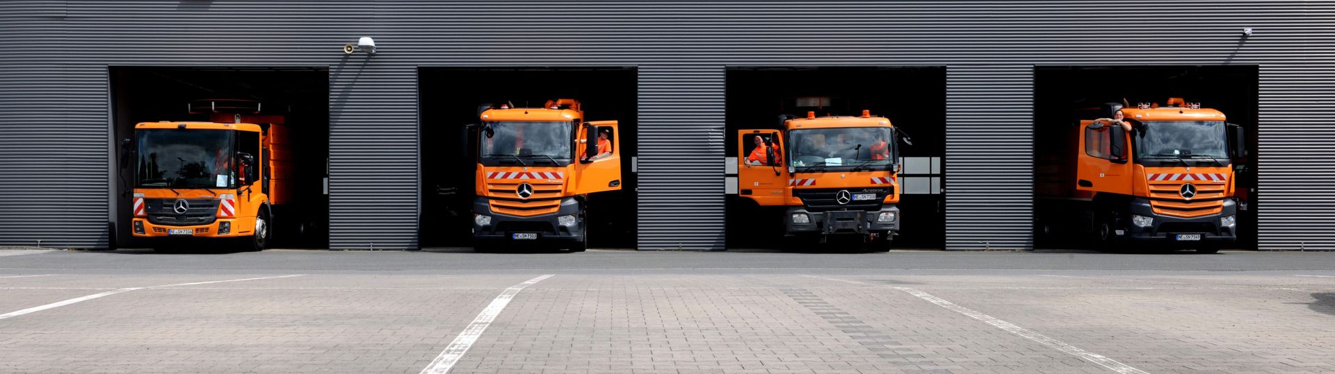 Werkhalle der Infrastruktur Neuss mit geöffneten Werktoren in denen Arbeitsfahrzeugen zu sehen sind.